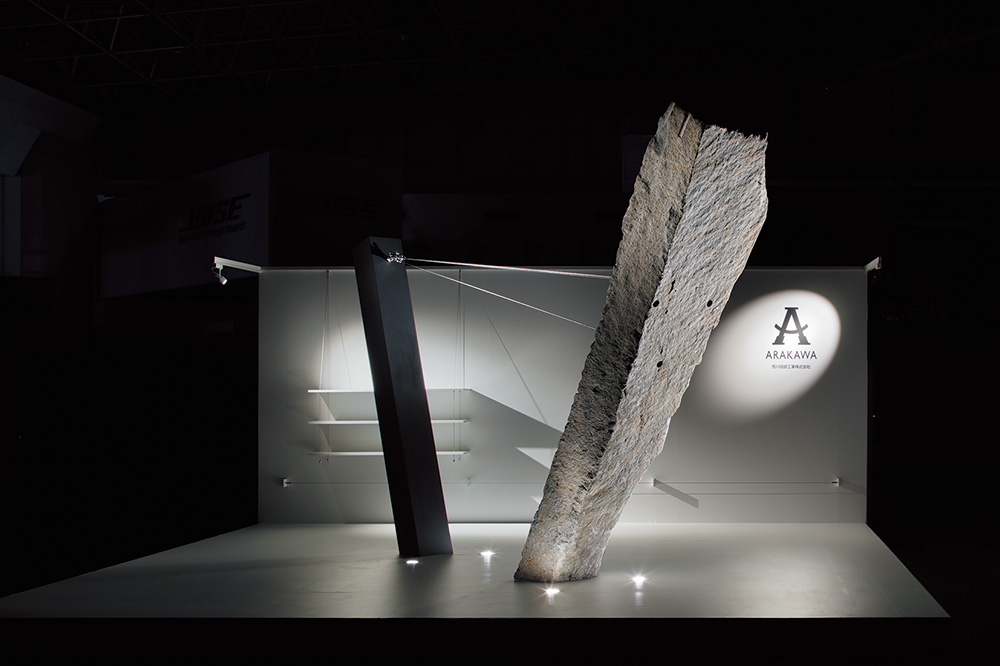 橋本夕紀夫デザインスタジオによるJAPAN SHOP2016の展示ブース。重さ約1.5tの巨大な岩を3本のワイヤーで支えている。
