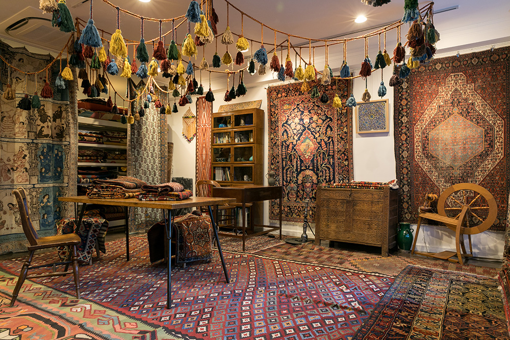 遊牧民カシュガイ族の飾りであるマングレが天井から吊るされた店内。ソレマニエ・フィニィ工房のものとビンテージ＆アンティークの製品を合わせて常時130点あまりの絨毯や小物がそろっている