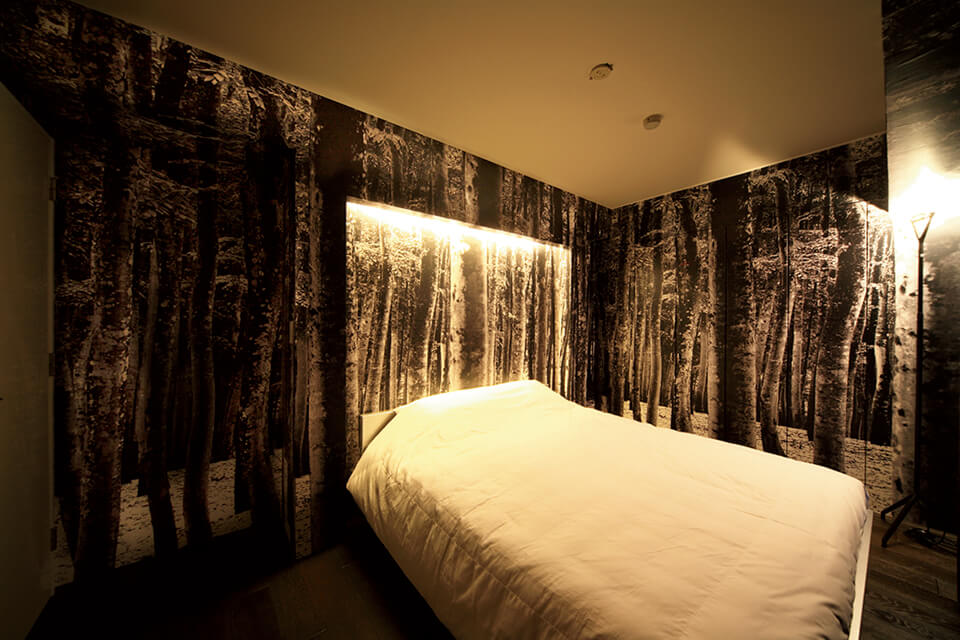 寝室の壁には、森の写真をデジタルプリントしたオリジナルのクロスを施し、静けさが感じられる空間を表現