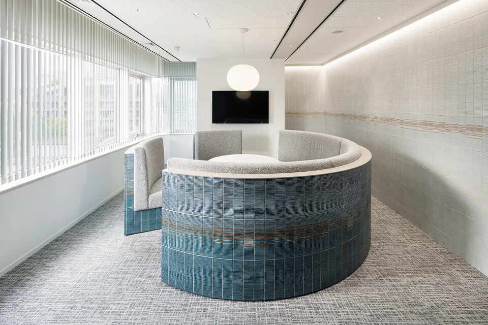 応接室には、磁器質タイル「Scenery Lines」（300×75 ㎜）を使用。壁にはホワイト、と円形ソファの背面にはブルーを配した