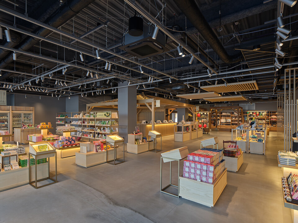 2026年3月に第1期リニューアルオープンした京都「太秦映画村」にて、最初に来場者を迎えるスーベニアショップ「本陣 お土産処」。黒いスケルトン天井に溶け込むように、オーディオテクニカのネットワークシーリングスピーカー「ATSP-30LP」が吊られている