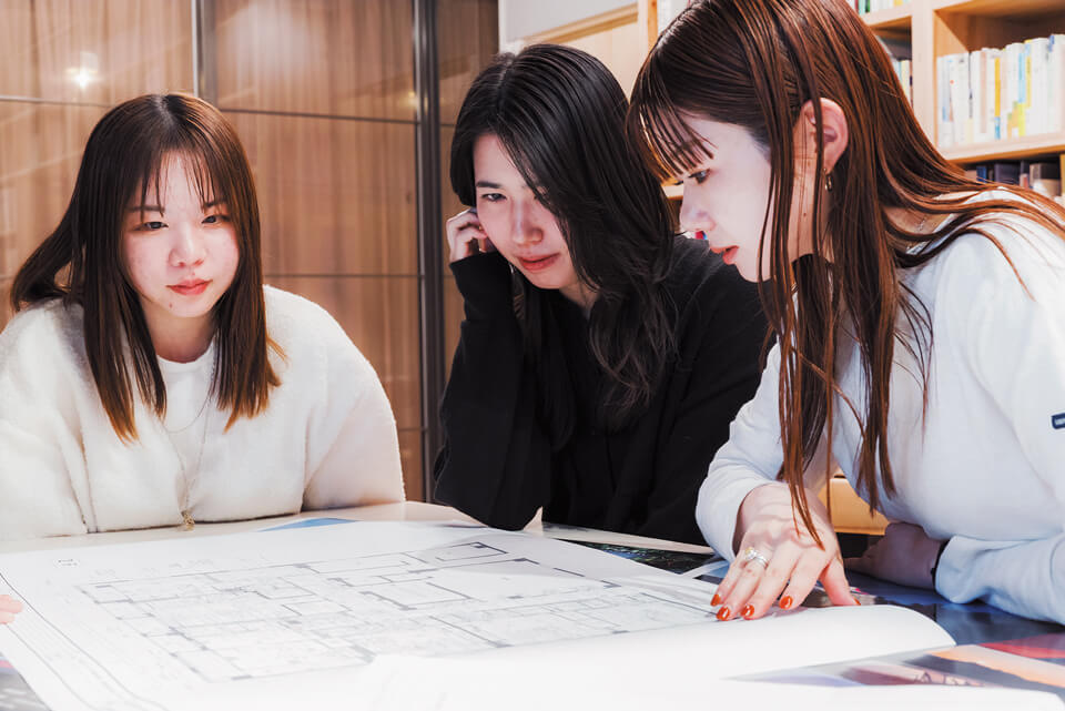 高精細プリンターが再現したA1図面をチェックする３人。「精度の高いA1プリントだから、デジタル画面では気づけない線の太さや文字の判読性のミスを発見できる」と佐藤さん