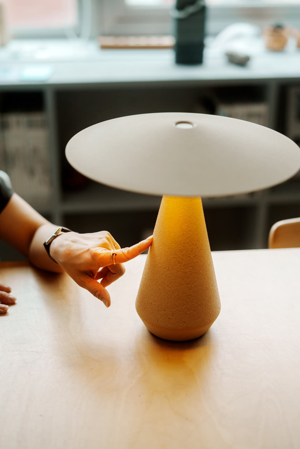 「T-Lamp」砂と鉄粉を混ぜた釉薬による、細やかな凹凸や焼きムラの表情を手で確かめる永山氏。均質な工業製品とは異なる、瀬戸焼ならではの素材感と手仕事の豊かさに触れた。カラーは Beige(写真)、Brick、Whiteの3色展開でサイズはSとL(Whiteのみ)の2種を用意